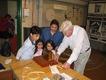 Visitors Jehan, Jasmine, Jenai & Chinoy with
             Geoff, G7KLV watching the tape come out.